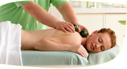 Edelsteinmassage am Rücken mit grünen Steinen